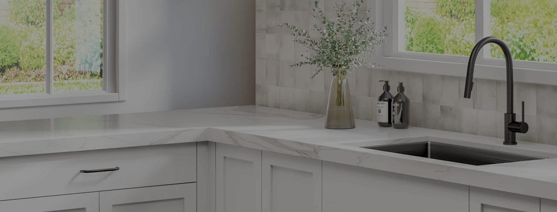 Modern kitchen with white cabinets, black fixtures, and natural light coming through windows showing greenery outside